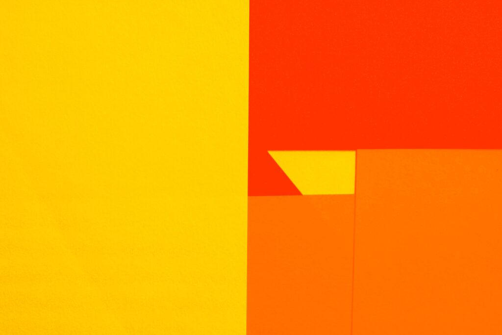 Colorful abstract image featuring bold geometric shapes in yellow, orange, and red.